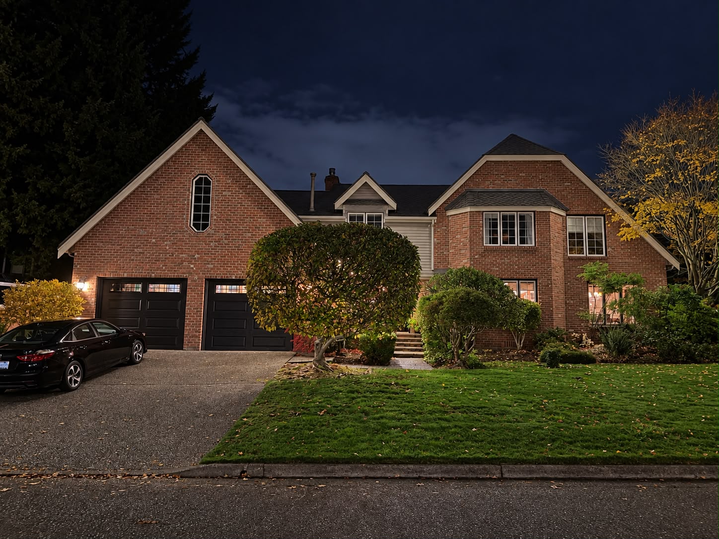 The same brick home at night before lighting installation